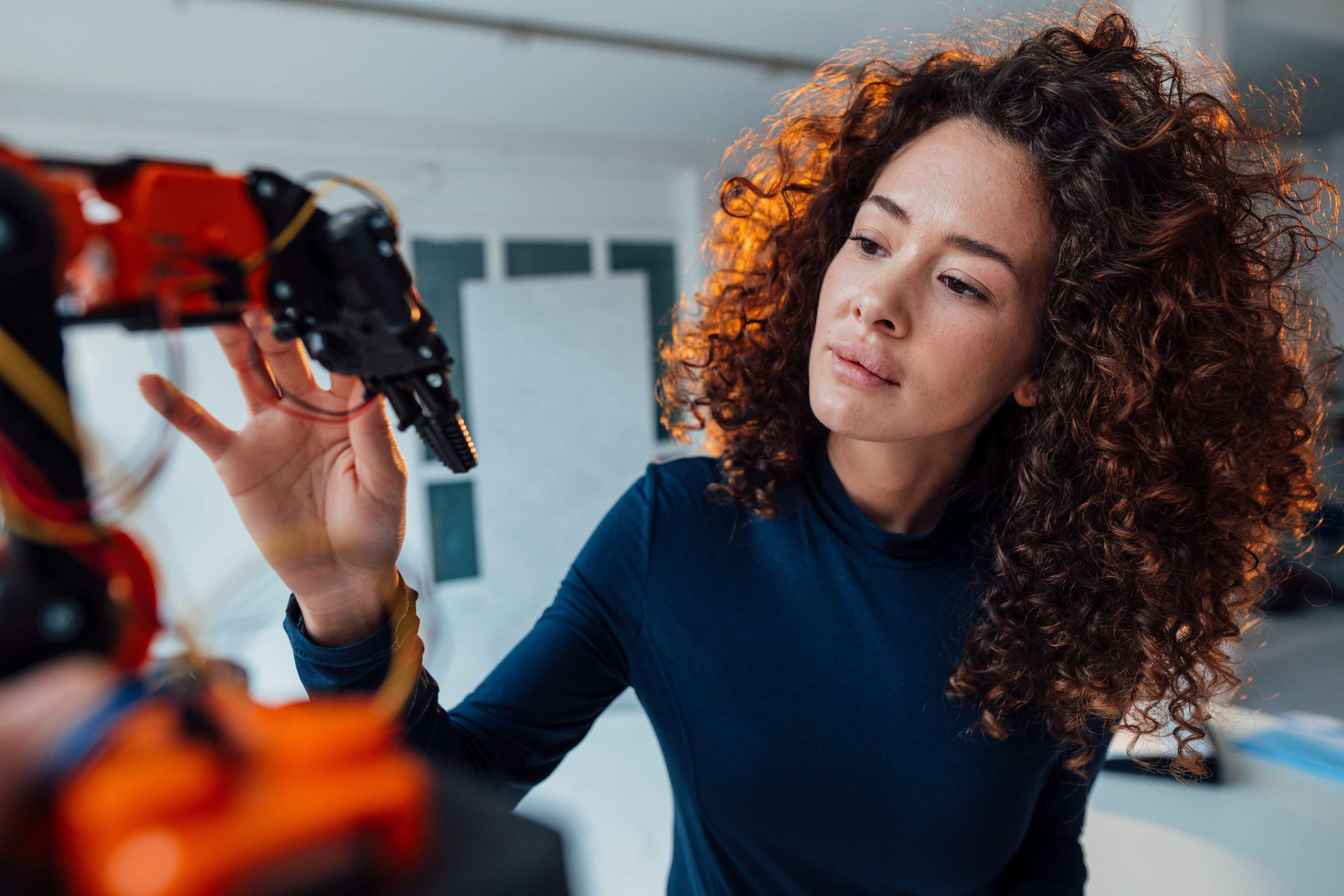 A woman inspecting a robotic arm.